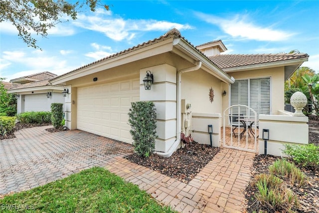 exterior space featuring a tiled roof, decorative driveway, an attached garage, and stucco siding