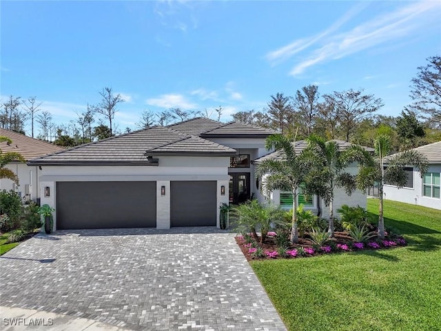 view of front of house with a tiled roof, an attached garage, decorative driveway, a front yard, and stucco siding