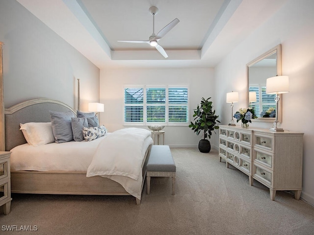 bedroom featuring carpet floors, a tray ceiling, ceiling fan, and baseboards