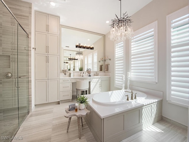 full bathroom with a chandelier, a stall shower, a garden tub, and vanity