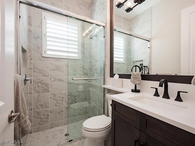 bathroom with a stall shower, vanity, and toilet