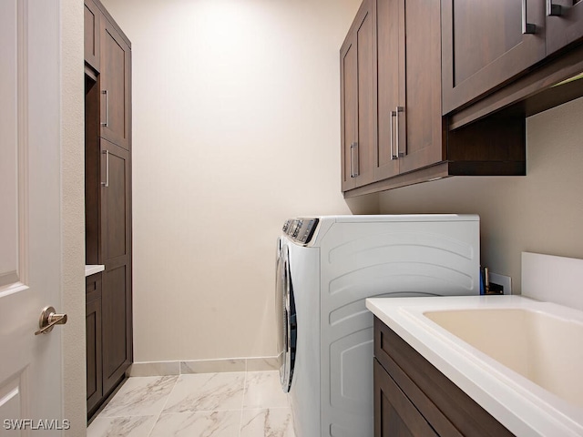 clothes washing area with marble finish floor, washer and clothes dryer, cabinet space, a sink, and baseboards