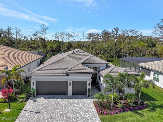 view of front of property featuring a garage, a tile roof, decorative driveway, and a front yard