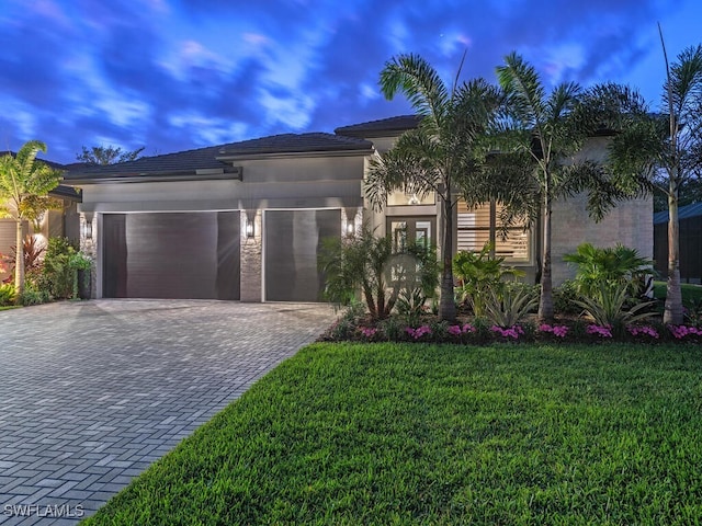 view of front of home featuring a front yard, decorative driveway, an attached garage, and stucco siding