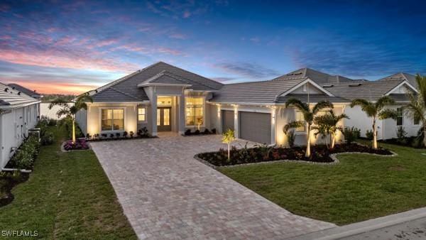 view of front of house featuring an attached garage, decorative driveway, and a front yard