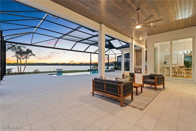 view of patio / terrace featuring glass enclosure, ceiling fan, and a water view