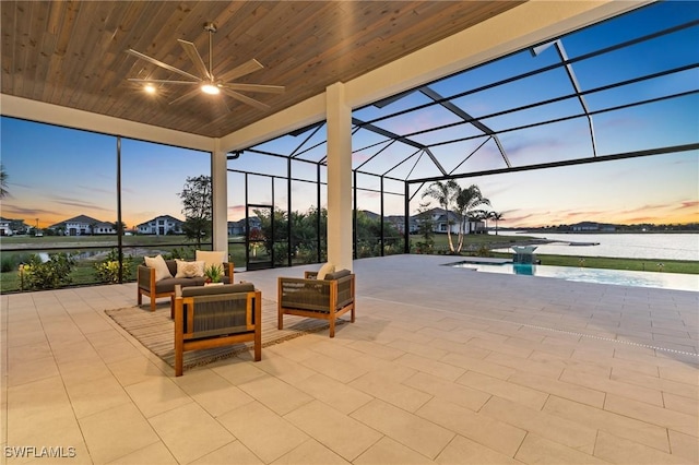 view of patio with an outdoor living space, glass enclosure, a water view, and a ceiling fan