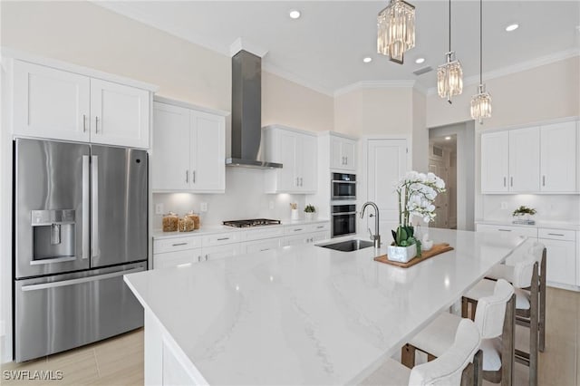 kitchen featuring wall chimney range hood, ornamental molding, appliances with stainless steel finishes, a large island, and a sink