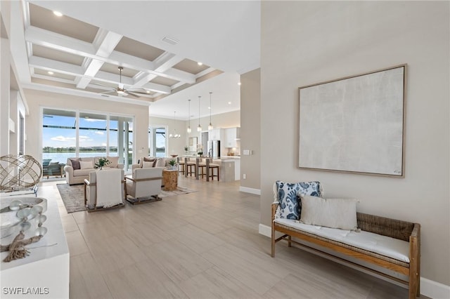 living area with baseboards, ceiling fan, beam ceiling, a high ceiling, and coffered ceiling