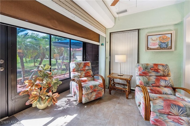 living area with light tile patterned floors, a ceiling fan, and visible vents