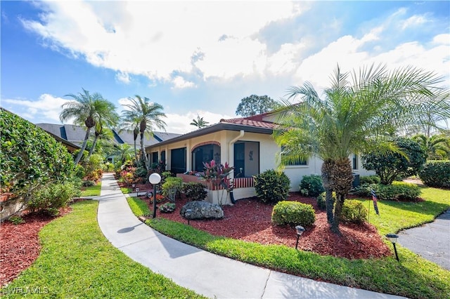 mediterranean / spanish house with a front lawn and stucco siding