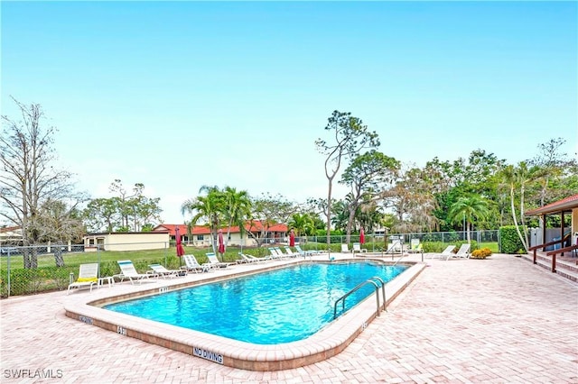 community pool with a patio area and fence