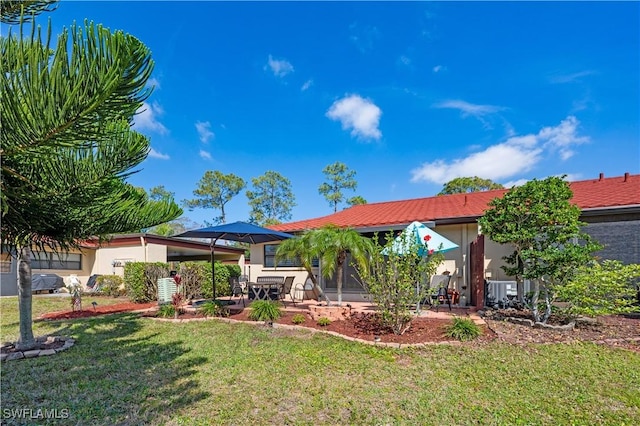 rear view of house with a patio, a lawn, and stucco siding