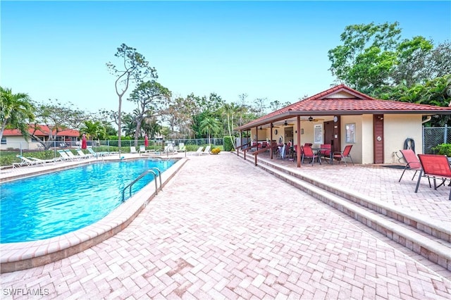 pool with a patio, a ceiling fan, and fence