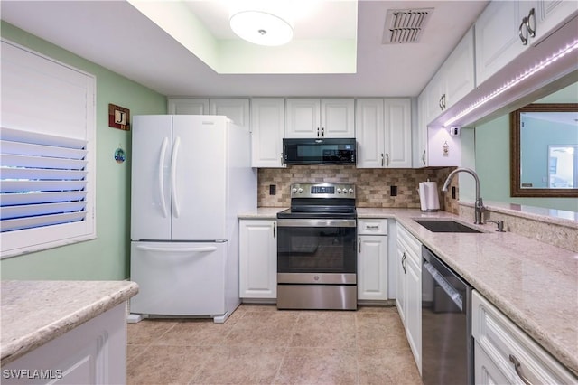 kitchen featuring visible vents, a sink, stainless steel appliances, a raised ceiling, and backsplash