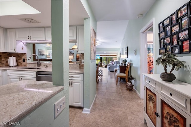 kitchen with visible vents, a sink, tasteful backsplash, stainless steel dishwasher, and white cabinets