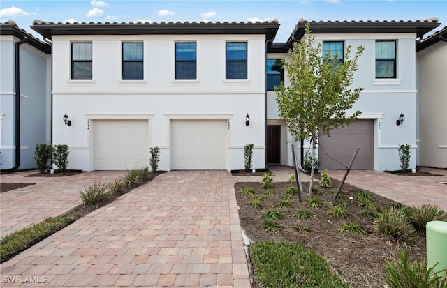 view of front of home with a tile roof, driveway, an attached garage, and stucco siding