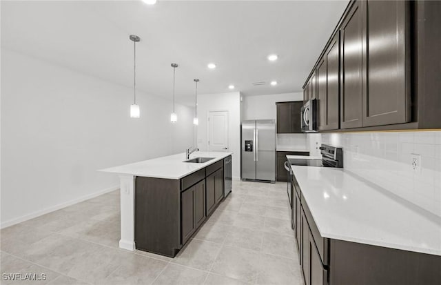 kitchen featuring pendant lighting, a center island with sink, light countertops, appliances with stainless steel finishes, and a sink