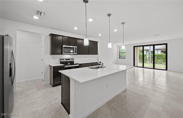 kitchen with visible vents, an island with sink, appliances with stainless steel finishes, decorative light fixtures, and light countertops