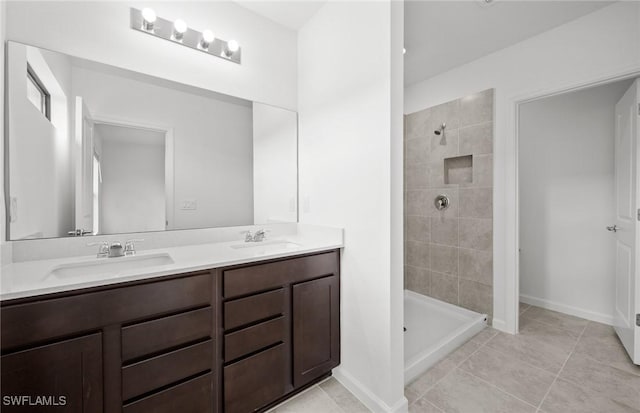 bathroom featuring double vanity, a stall shower, a sink, and baseboards