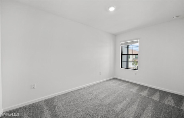 empty room featuring carpet and baseboards