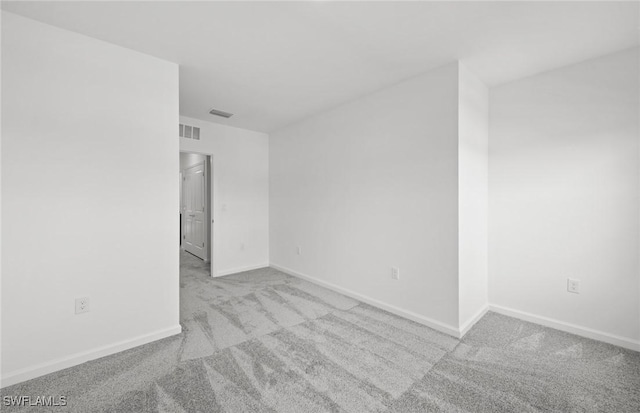 empty room with light carpet, visible vents, and baseboards