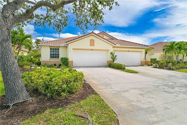 mediterranean / spanish house with a garage, concrete driveway, a tile roof, and stucco siding