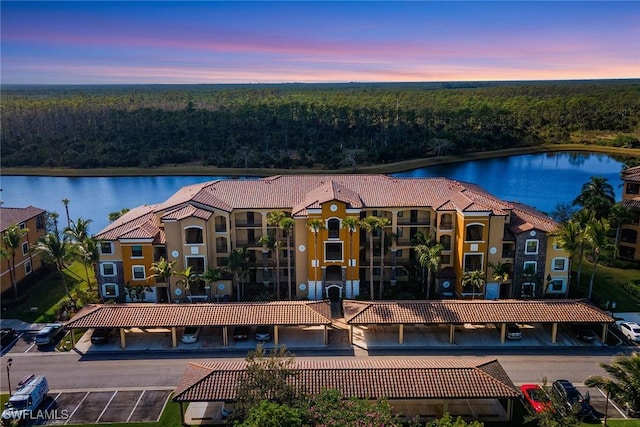 exterior space featuring a tile roof, a water view, and a wooded view