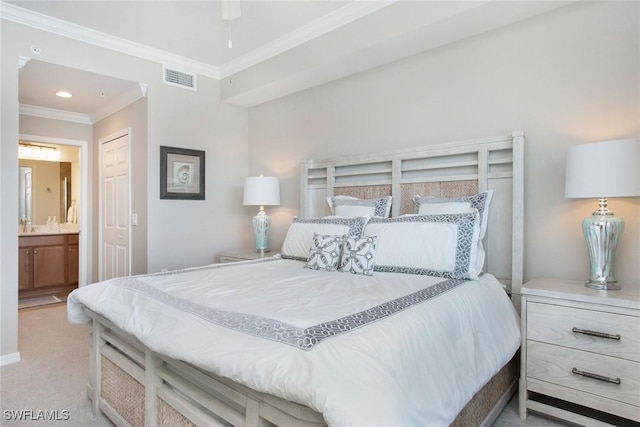 bedroom with a closet, visible vents, ornamental molding, carpet flooring, and ensuite bath