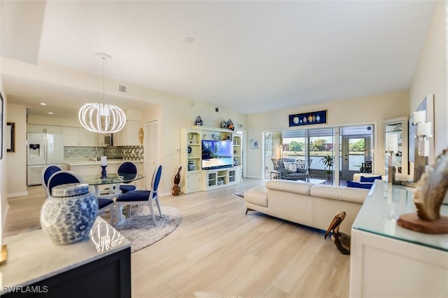 living room with a chandelier, light wood-type flooring, baseboards, and recessed lighting