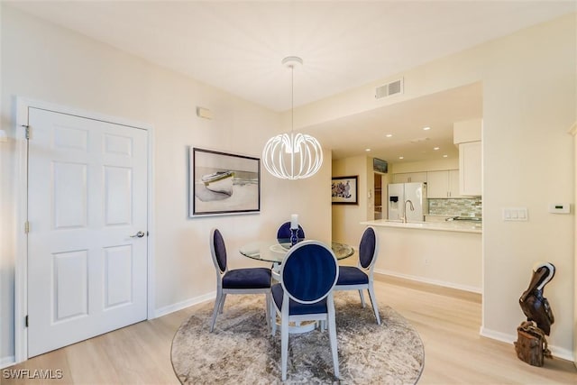 dining space with light wood-style floors, visible vents, a notable chandelier, and baseboards