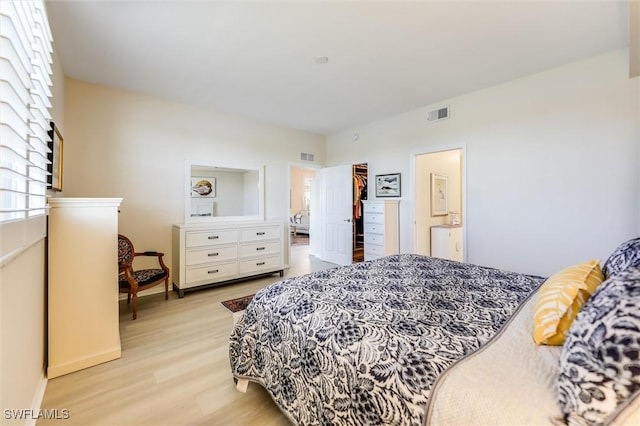 bedroom with light wood-type flooring, ensuite bath, baseboards, and visible vents