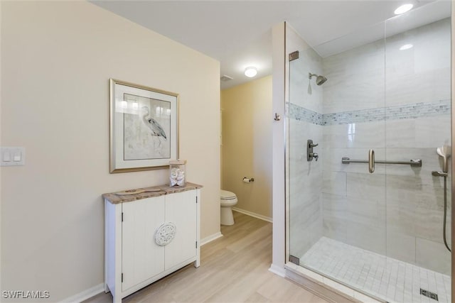 full bathroom with toilet, a stall shower, baseboards, and wood finished floors