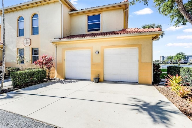 mediterranean / spanish-style house featuring driveway, an attached garage, a tiled roof, and stucco siding