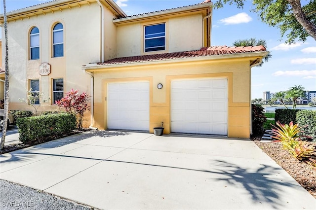 view of front of property featuring stucco siding, a tile roof, driveway, and a garage