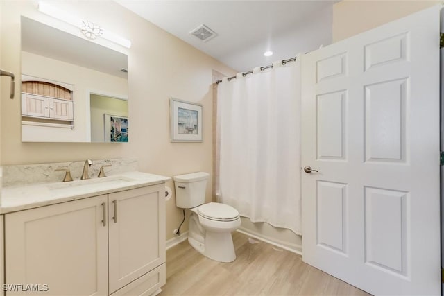 bathroom with visible vents, toilet, shower / tub combo, vanity, and wood finished floors