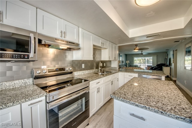 kitchen featuring visible vents, a peninsula, stainless steel appliances, under cabinet range hood, and a sink