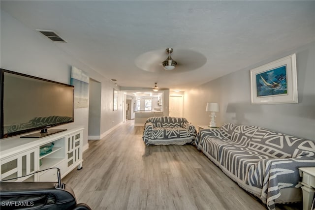 living room with ceiling fan, wood finished floors, visible vents, and baseboards