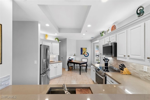 kitchen featuring light tile patterned floors, tasteful backsplash, appliances with stainless steel finishes, a tray ceiling, and recessed lighting