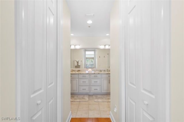 full bath featuring tile patterned flooring, a closet, a sink, and double vanity