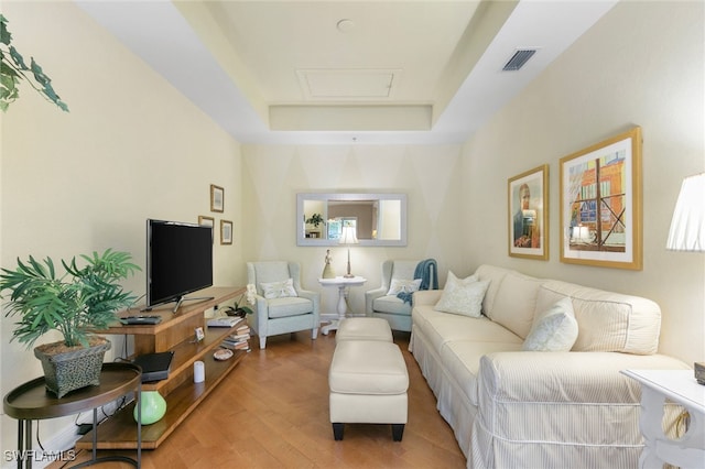 living room featuring light wood-type flooring, a raised ceiling, and visible vents