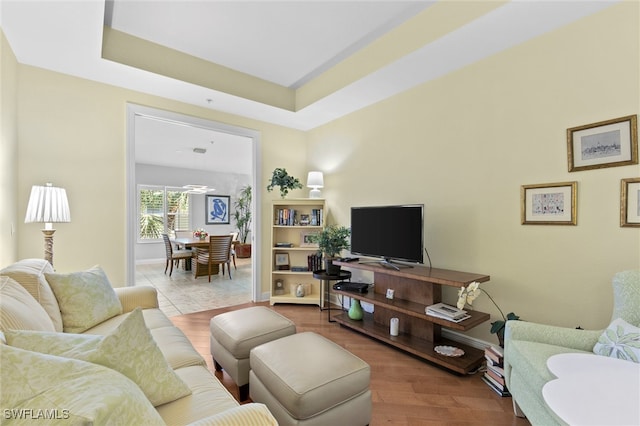 living area with a raised ceiling, wood finished floors, and baseboards