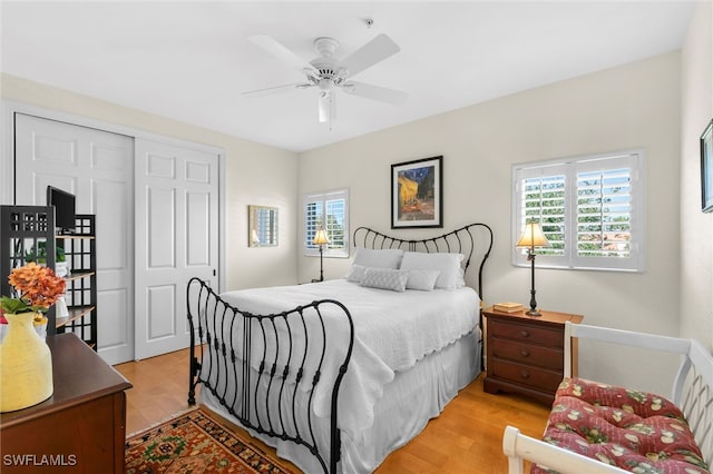 bedroom featuring light wood-style flooring, multiple windows, a ceiling fan, and a closet