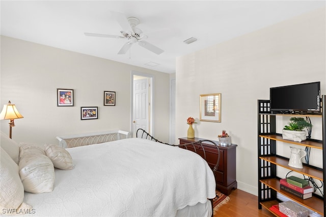 bedroom featuring a ceiling fan, wood finished floors, visible vents, and baseboards