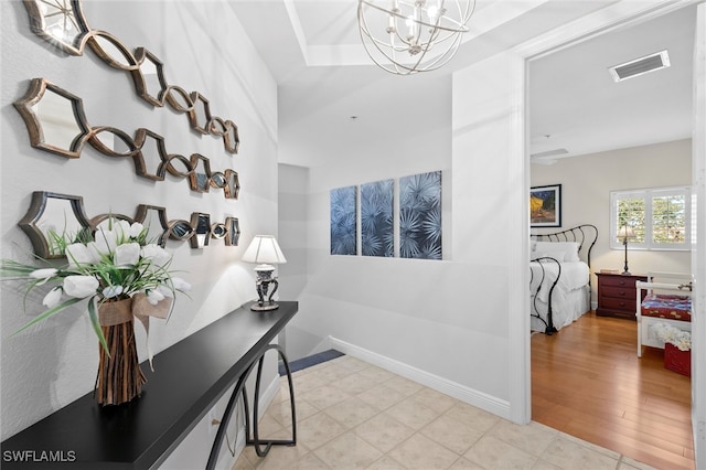 interior space with a notable chandelier, baseboards, visible vents, and wood finished floors