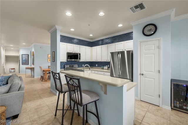 kitchen with stainless steel appliances, light countertops, visible vents, white cabinetry, and an island with sink