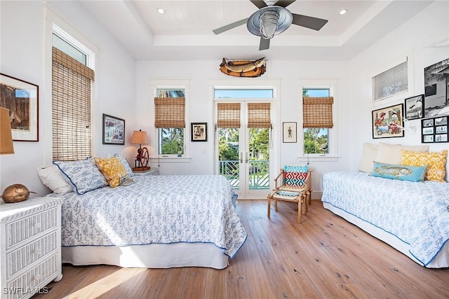 bedroom with access to exterior, wood-type flooring, a tray ceiling, and french doors