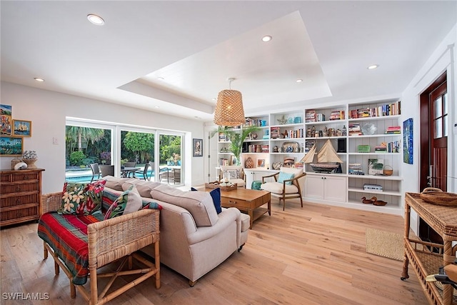 living area featuring light wood finished floors, a tray ceiling, and recessed lighting