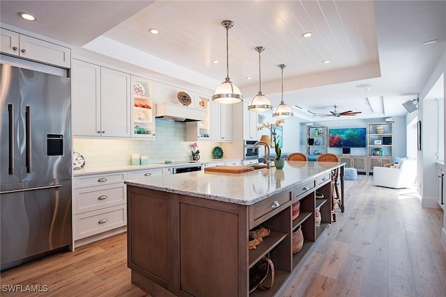 kitchen with open floor plan, appliances with stainless steel finishes, open shelves, and a raised ceiling