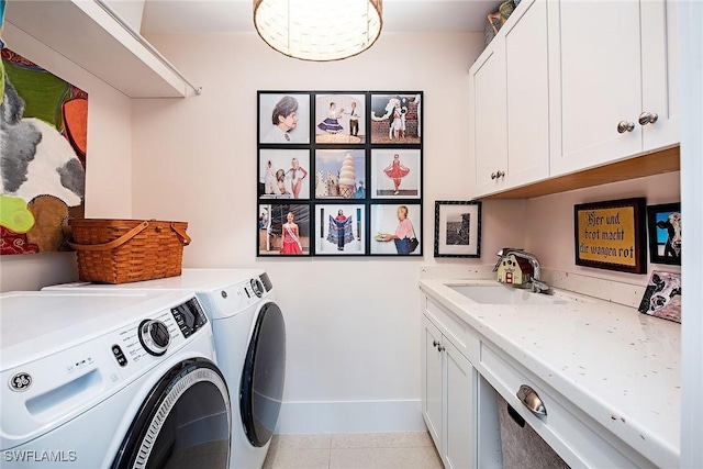 washroom with cabinet space, washing machine and dryer, baseboards, and a sink